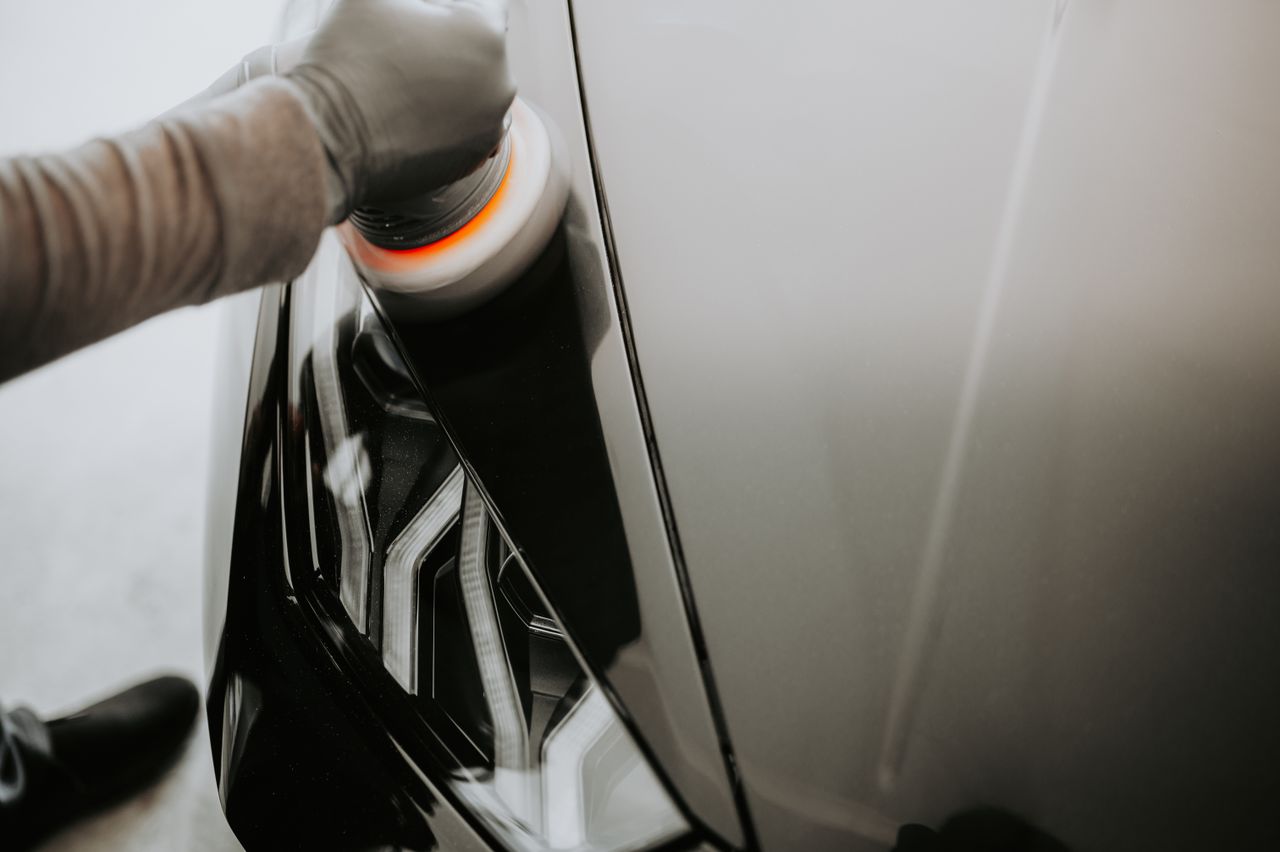 digital Close-up view of a person polishing a black car using a buffing machine.
