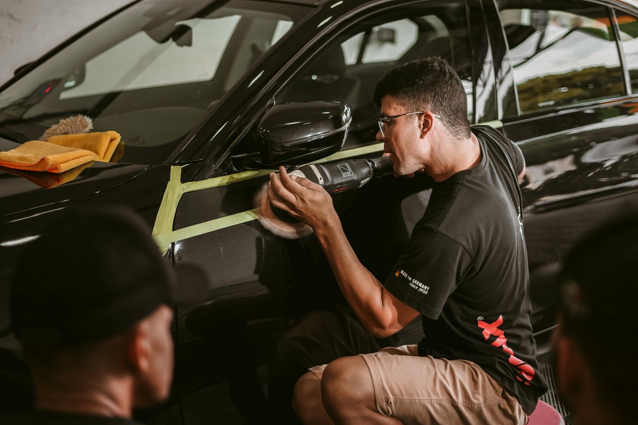 digital-01 A man meticulously polishes a car, showcasing precision in an automotive workshop.